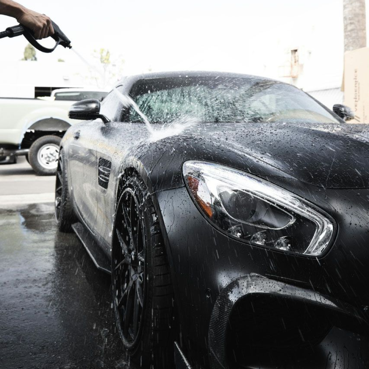 Black sports car being washed by a detailer